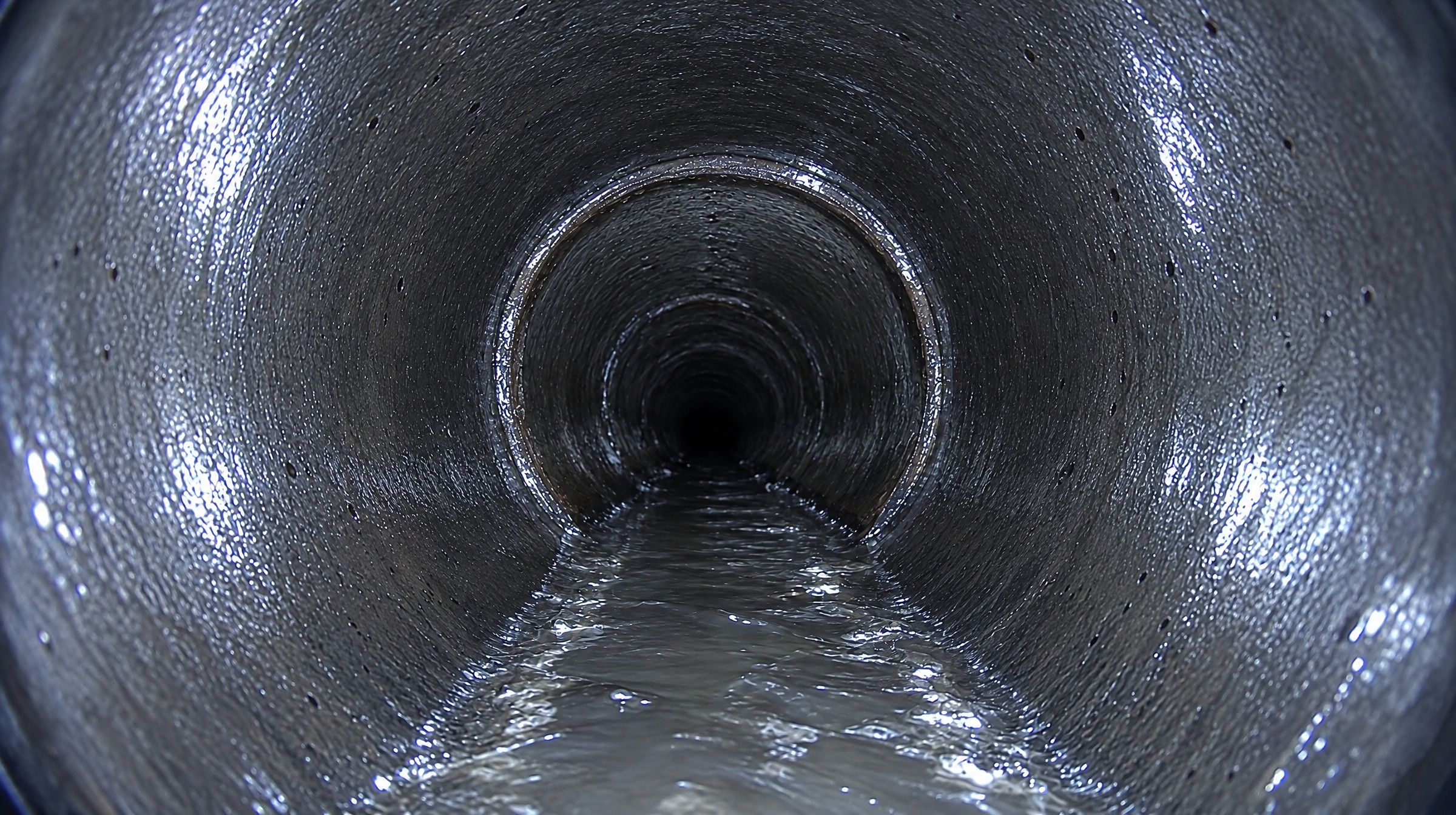 La même canalisation en fonte après hydrocurage, paroi propre et eau qui s'écoule