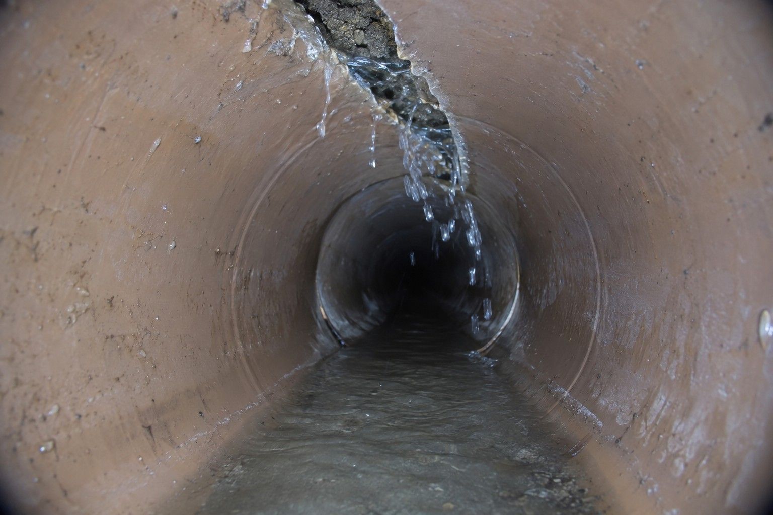 Fissure sur une canalisation enterrée par laquelle l'eau s'infiltre, vue par la caméra d'inspection