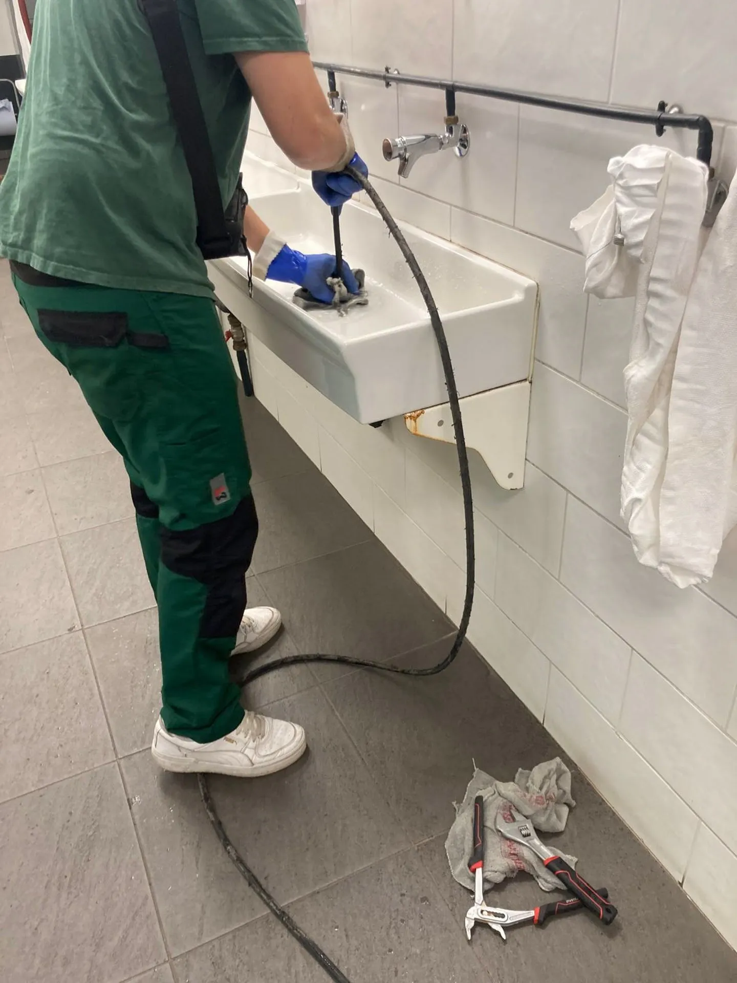 Technicien passant un furet dans l'évacuation d'un lave-mains