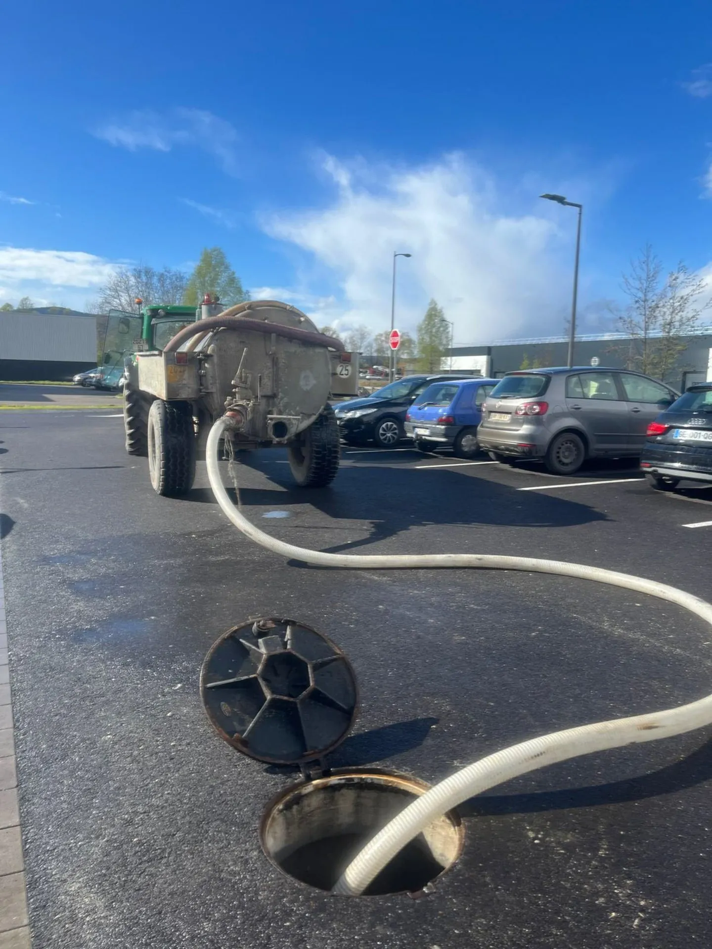 Tonne de pompage sur un parking, flexible engagé dans un regard ouvert